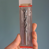 Drill bit in packaging held by a hand against a gray background