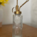 Clear glass bottle with brass pump on a wooden surface
