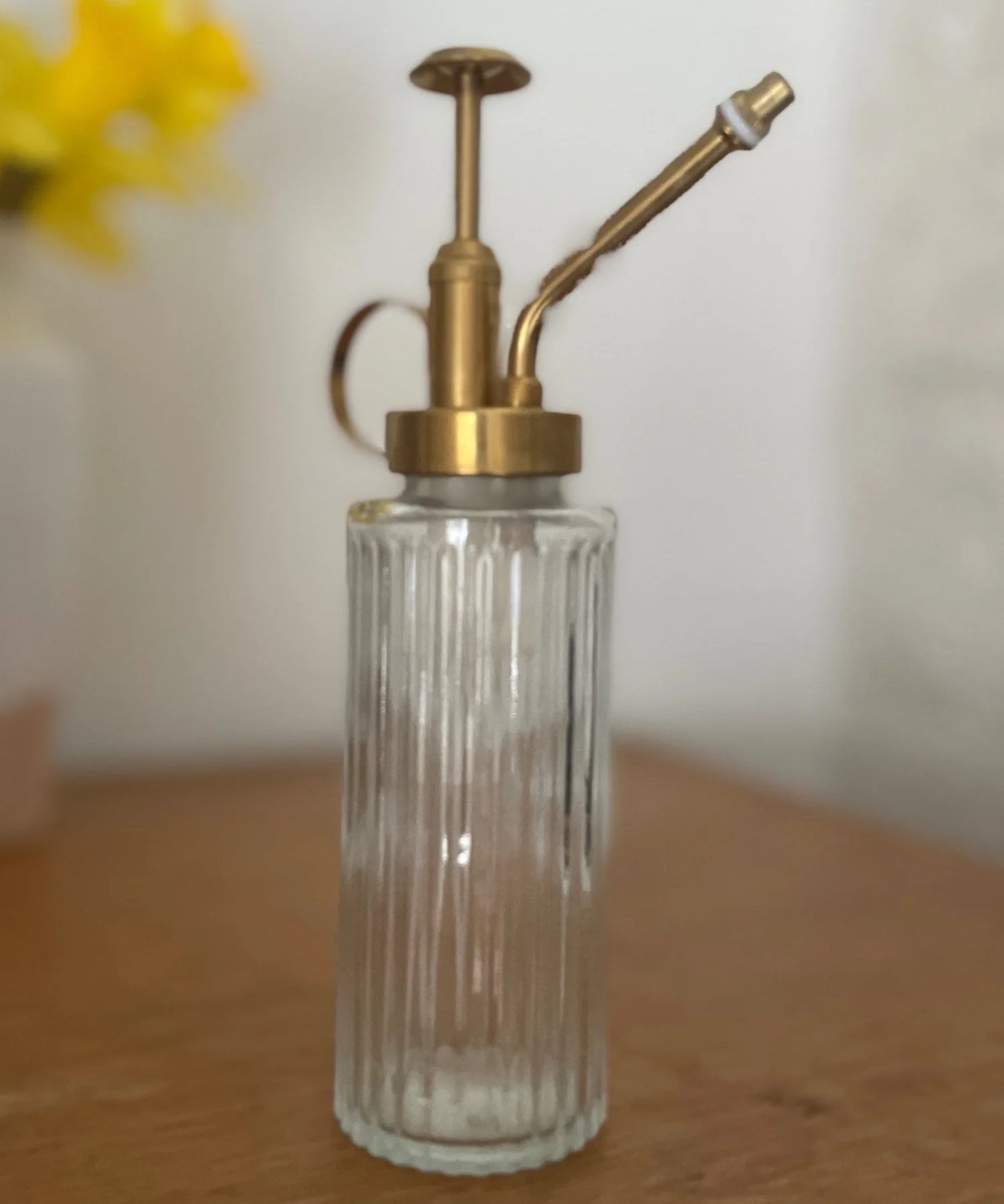 Clear glass bottle with brass pump on a wooden surface