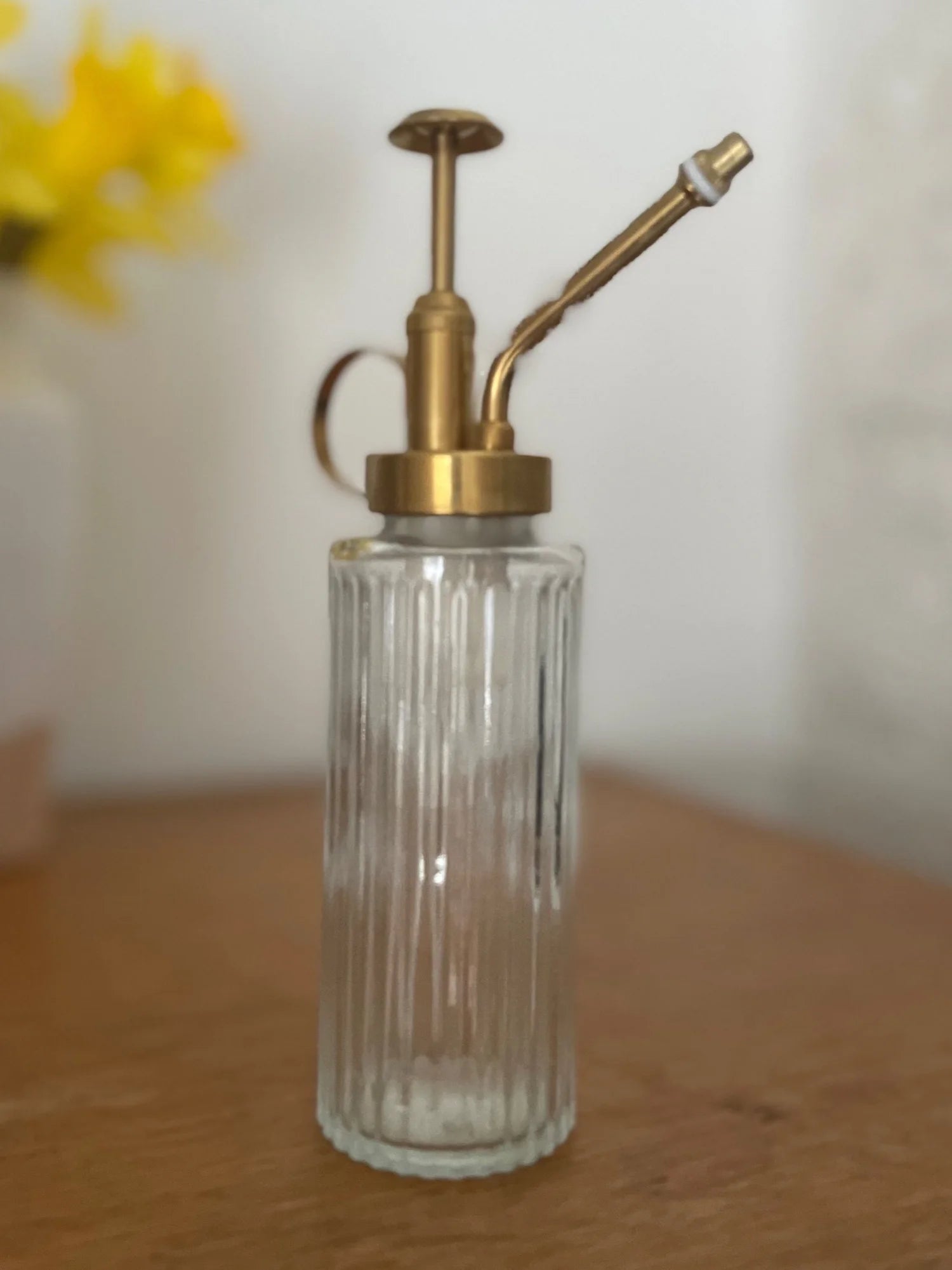 Clear glass bottle with brass pump on a wooden surface