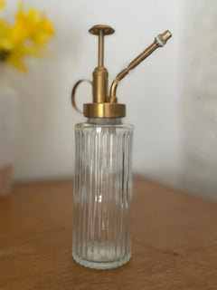 Clear glass bottle with brass pump on a wooden surface